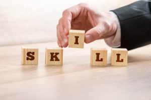 Close up Businessman Hand Arranging Wooden Blocks on Top of the Table to Form Skill Word.