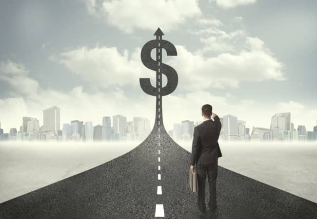 Businessman standing on a road pointing at dollar sign, highlighting pricing.